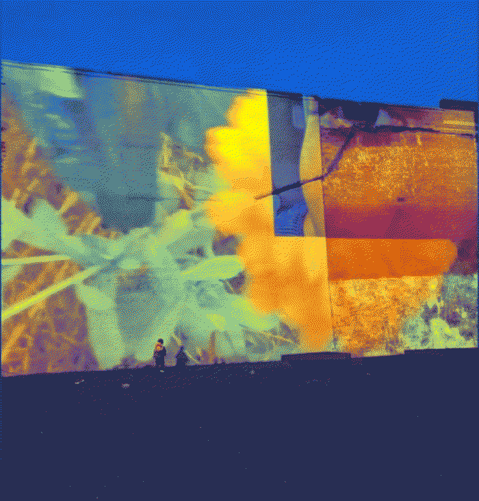 an image of the artwork being projected onto a building at night with a person standing in front of it
